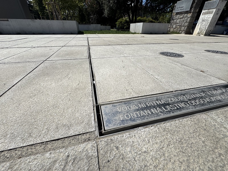 Detajl odvodnjavanja fontane z ACO SlotTop kanaleto z rego, ki je dimenzijsko prilagojena rastru in demenzijam kamnitega tlakovanja